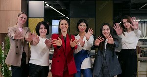 Friendly female team welcoming in office. Smiling women in business attire extending warm greetings, unity and positive workplace culture. Corporate environment and professional camaraderie.