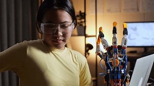 Close Up Of Teen Asian Girl Having A Backache While Working About A Cyborg Hand On A Laptop At Home