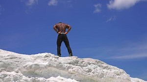 Strong athletic male model portrait. African american man bodybuilder posing on the rock