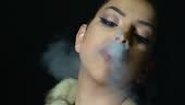 Close up portrait of a young Caucasian woman exhaling a cigarette...