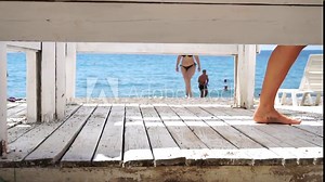 Woman in the changing, dressing room on beach, at sunset on the seashore. Close-up of bare female feet legs in enclosed changing room cabin. Summer holiday vacation and travel concept. Slow motion