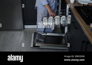 Side view of woman loading dishwasher with dirty plates, bowls, cutlery, and cups. Everyday kitchen routine showing dishwashing preparation at home Stock Video Footage - Alamy