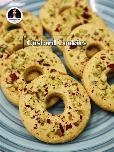 Custard cookies are delightful, melt-in-your-mouth treats that feature the rich and distinctive flavor of custard powder. Ingredients: For the Cookie Dough: - 1 cup (120g) Maida (All-purpose flour) - 50g Salted Butter - 3 tbsp Powdered Sugar - 2 tbsp Custard Powder - 2 tsp Milk Powder - 1/4 tsp Vanilla Essence - 1/4 tsp Baking Soda - 3 tbsp Milk To Garnish the Cookies: - 2 tbsp Chopped Pistachio - 1 tsp Rose Petals Instructions: 1. Prepare a baking tray by greasing and lining a with butter and p