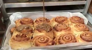 Maple icing going on homemade cinnamon rolls fresh out of the oven! | Beasley's Orchard