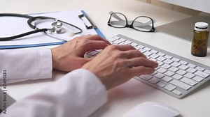 Woman doctor typing medical receipt to patient. Female physician working at computer in clinic.