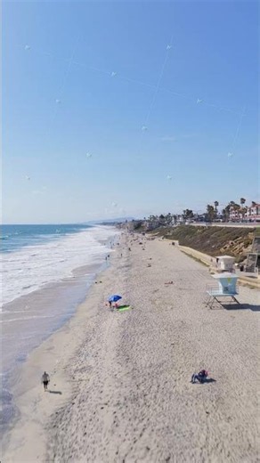 People sunbathing and relaxing on Carlsbad State Beach seashore in California. Flying above sand