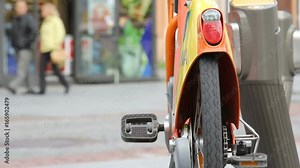 City Bike Rent. Bike parking. Public bicycle sharing system. Bicycle rental machine. Crowd people in the background. 24
