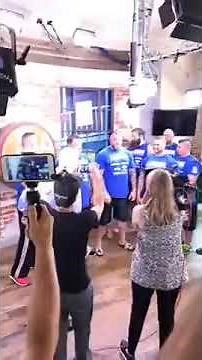 strongman overhead lifting the reporter one arm