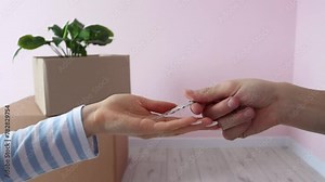 Stockvideon Handing over the keys of a house by a real estate agent to a young woman who rented or bought an apartment. Close-up of the hand of the former homeowner handing the key to the new owner in slow motion