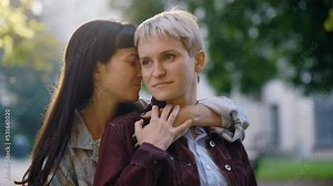 Lesbian family standing outside, one partner hugging her girlfriend, touching hands . Lgbt woman, showing love to each other. Happy lesbian relationships. Lesbian girlfriend caressing her partner