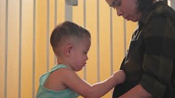 Asian little baby boy is hungry for milk. Trying to unbutton her...