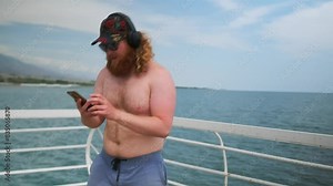 Funny man bare chested dancing on pier with sea wind, expressing joy and relaxation from freedom on vacation. Mid shot.