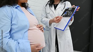 Mid-section video of a female doctor gynecologist holding clipboard with analyses and ultrasound scan results, explaining to a pregnant woman the treatment that needs to perform in obstetric clinic