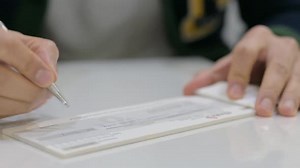 Hand Signing a cheque in Bank