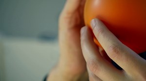 Inflating an orange balloon in a slow motion. Free HD video footage