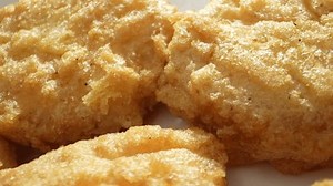 Chicken nuggets: bite-sized chicken, breaded, fried and baked till crispy outside, tender inside. Popular fast food, loved by all ages globally. Shot with 24mm probe macro lens. Food background. 4K.