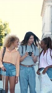 Three Multiracial Friends Looking at the Photos in a Camera in Madrid Spain