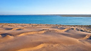 Onde a areia clara encontra o oceano azul profundo em contraste perfeito