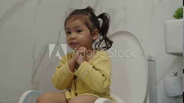 happy toddler girl is sitting on the toilet at home. potty training and learning