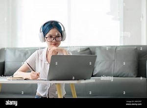 Happy young woman teenage wearing headphones writing note. student online learning class study online video call zoom teacher with laptop and book Stock Photo - Alamy