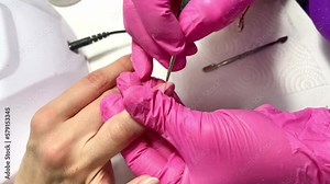 Professional manicure master applies a nude-colored gel polish to the nail. Manicure process, the service of the client's nail care services. Applying nail polish in a beauty salon.