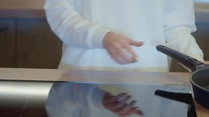 The woman cook turned on the stove. ACTION. The cook put the frying pan on the stove. Woman in a white tunic cook in the kitchen