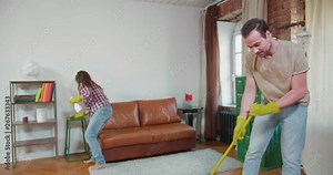 young married couple do house cleaning together.