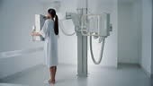 Beautiful Multiethnic Woman in Medical Gown Standing Next to X-Ray...