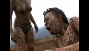 Two Asian girls wrestling on manure field