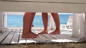 Two woman in the changing, dressing room on beach, at sunset on the seashore. Close-up of bare female feet legs in enclosed changing room cabin. Summer holiday vacation and travel concept. Slow motion