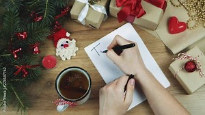 Woman hands writing new year to do list on white paper sheet, planning her future. Christmas decoration with fir branches, gifts. Flat lay. Top view. Mockup, copy space for your text.