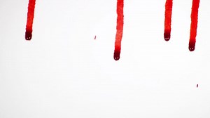 Premium stock video - Blood droplets on white background dripping down white surface