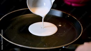 Closeup of making steaming hot crepe layer on a cast iron pan. A thin pancake made with rice flour dough and condensed milk stuffing. Thin batter being spread and cooked for making 'Pithe' and 'dosa' 素材庫影片