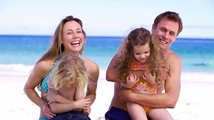 Parents hugging their children on the beach