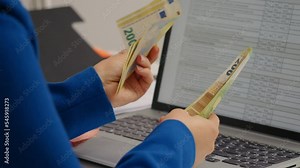 Side view woman that counts money in bills in front of a laptop. Female cashier counting eutopean cash money.
