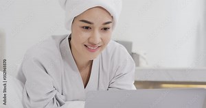 Beautiful asian woman using laptop at bed. She using computer for online work with smile.