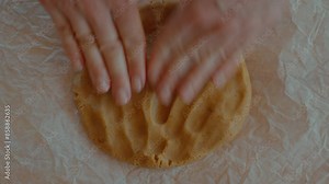 Process of preparing dough for gingerbread cookies. Top down table view on female baker hands roll and flatten dough for preparing baked biscuits