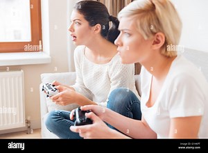Two girlfriends playing video games with joystick Stock Photo - Alamy