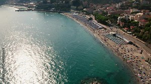 Drone shot tilting up to the crowded beach of Celle Ligure in the Italian region Liguria
