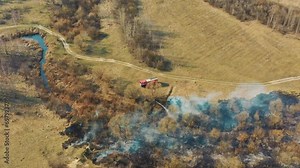 Aerial View. Spring Dry Grass Burns During Drought Hot Weather. Bush Fire And Smoke. Fire Engine, Fire Truck On Firefighting Operation. Wild Open Fire Destroys Grass. Ecological Problem Air Pollution.