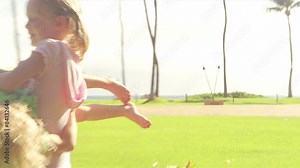 Two young sisters play with each other in the grass