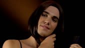 Glad transgender combing wig hair admiring reflection, feeling like...