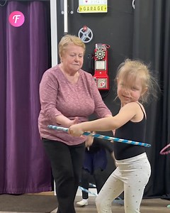 Mädchen bekommt eine helfende Hand bei dem Versuch, einen Hula-Hoop-Reifen zu beherrschen | Fabiosa Deutschland