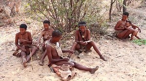 RUNDU, NAMIBIA - SEPT. 13, 2014: Rare footage of elusive San People or Bushmen of the Kalahari. Indigenous hunter-gatherer peoples of Africa. Group of women, young and old, with babies breastfeeding.