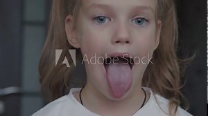 Child girl opens her mouth wide. child shows her teeth and mouth to dentist. mouth is wide open, tongue is stuck out as far as possible, with clear view of tongue and soft palate
