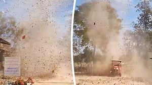 Dog and tractor dodge spinning dust devil on Thai farm