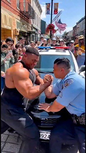 Bodybuilder Challenges a Cop… and LOSES! 🚓💪😂 On a sunny American street 🇺🇸☀️, a massive bodybuilder challenges a police officer 🚓 to an arm wrestling match — right on the hood of his patrol car! 💪😂 A crowd gathers, phones out, cheering and laughing 📱👏 The bodybuilder flexes proudly, but the cop stays calm and focused 😎 Then suddenly — the cop WINS with a playful smile and a salute! 🇺🇸💥 The crowd erupts in laughter and applause — pure American fun energy! 🎉 #CopVsBodybuilder #OnlyI