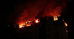 Huge fire blazing in residential building. House is engulfed in flames at night during the disastrous