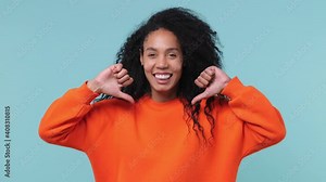 Confident smiling cheery young african woman with curly hair 20s years old wearing basic casual orange sweatshirt pointing fingers on herself isolated on pastel blue color background studio portrait
