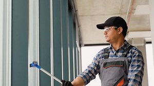 Asian male professional cleaning service worker cleans the windows and shop windows of a store with special equipment